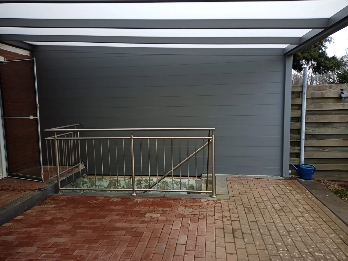 Festverglasung in Anthrazit als seitlicher Sichtschutz unter einer überdachten Terrasse mit Treppenzugang