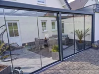 Terrassendach mit Glasschiebewand in der Eckansicht, dahinter ein Loungebereich