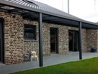 Langes Aluminium-Vordach entlang der Fassade eines Klinkerhauses