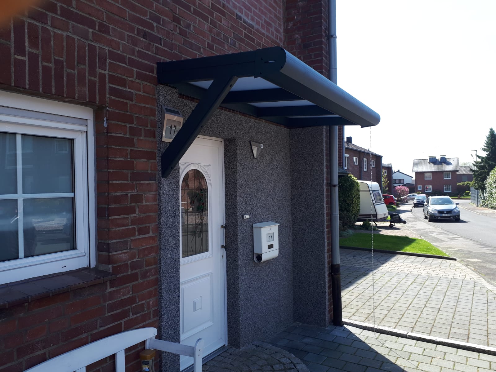Kompaktes Haustürvordach mit Streben an Klinkerfassade